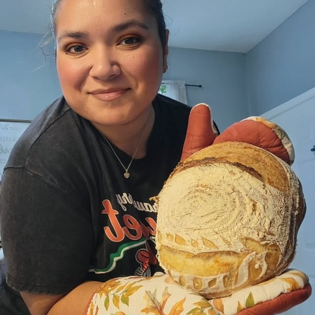 Baker Jas holding freshly baked sourdough loaf